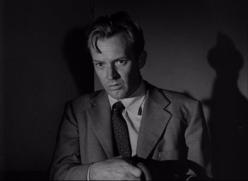 Movie still from “Champion” (1949), directed by Mark Robson – Black and white photograph of a man wearing a suit and tie; Close Up shot, Low angle