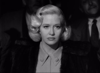 Movie still from “Champion” (1949), directed by Mark Robson – A black and white photo of a woman with blonde ringlets; Close Up shot, Low angle