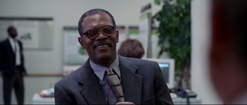Movie still from “Changing Lanes” (2002), directed by Roger Michell – A man in a suit and tie smiling for the camera; Close Up shot, Low angle