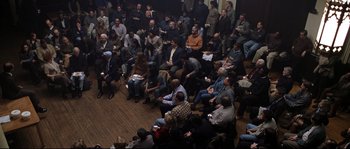 Movie still from “Changing Lanes” (2002), directed by Roger Michell – A group of people sitting in a large room; Wide shot, High angle