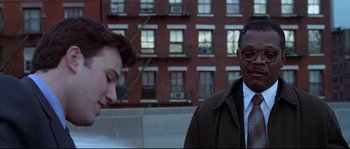 Movie still from “Changing Lanes” (2002), directed by Roger Michell – A man and a woman standing next to each other in front of a brick building; Medium shot, Over the shoulder angle