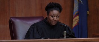 Movie still from “Changing Lanes” (2002), directed by Roger Michell – A woman wearing a black robe sitting in front of a microphone in a courtroom; Close Up shot, Low angle