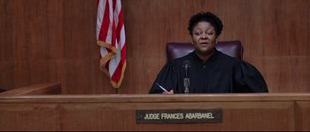Movie still from “Changing Lanes” (2002), directed by Roger Michell – A judge in a courtroom with a flag in the background; Medium shot, Low angle