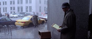 Movie still from “Changing Lanes” (2002), directed by Roger Michell – A man standing next to a yellow taxi cab in the pouring rain; Wide shot, Over the shoulder angle