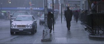 Movie still from “Changing Lanes” (2002), directed by Roger Michell – Two men walking down the street in the pouring rain; Wide shot, Low angle
