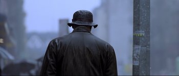 Movie still from “Changing Lanes” (2002), directed by Roger Michell – A man wearing a hat walking down a street; Close Up shot, Low angle