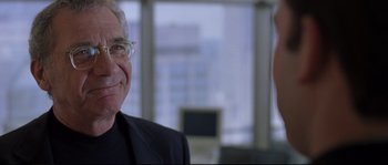 Movie still from “Changing Lanes” (2002), directed by Roger Michell – A man in a black suit and glasses smiling for the camera; Close Up shot, Over the shoulder angle
