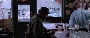 Movie still from “Changing Lanes” (2002), directed by Roger Michell – A man sitting at a table in front of a glass of water; Medium shot, Over the shoulder angle