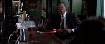 Movie still from “Changing Lanes” (2002), directed by Roger Michell – A man sitting at a table in front of drinks; Medium shot, Low angle