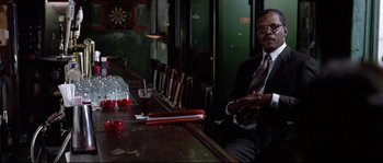 Movie still from “Changing Lanes” (2002), directed by Roger Michell – A man sitting at a table in front of drinks; Medium shot, Low angle