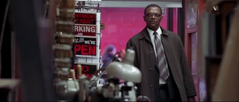 Movie still from “Changing Lanes” (2002), directed by Roger Michell – A man standing in front of a wall with a lot of signs; Medium shot, Over the shoulder angle