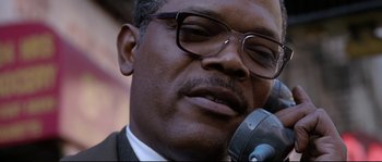 Movie still from “Changing Lanes” (2002), directed by Roger Michell – A person wearing glasses and holding a microphone; Close Up shot, Low angle