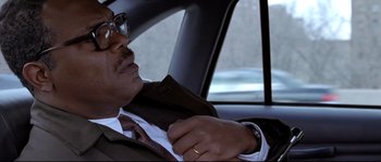 Movie still from “Changing Lanes” (2002), directed by Roger Michell – A man sitting in the back seat of a car wearing a suit; Close Up shot, Over the shoulder angle