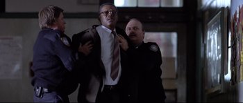 Movie still from “Changing Lanes” (2002), directed by Roger Michell – A man in a suit and a police officer in a uniform; Medium shot, Low angle