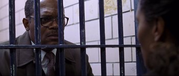 Movie still from “Changing Lanes” (2002), directed by Roger Michell – A man in a suit behind a metal fence; Close Up shot, Low angle