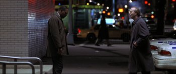 Movie still from “Changing Lanes” (2002), directed by Roger Michell – A man is standing on the sidewalk at night; Wide shot, Low angle
