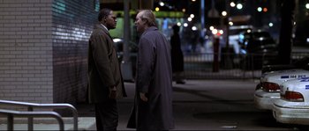 Movie still from “Changing Lanes” (2002), directed by Roger Michell – Two men standing next to each other on the sidewalk; Medium shot, Over the shoulder angle