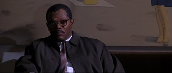 Movie still from “Changing Lanes” (2002), directed by Roger Michell – A man wearing a suit and tie sitting on a couch; Close Up shot, Low angle