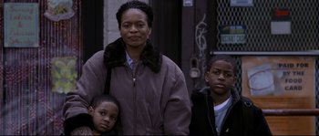 Movie still from “Changing Lanes” (2002), directed by Roger Michell – A woman and two young boys standing next to each other on the sidewalk; Medium shot, Low angle