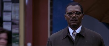 Movie still from “Changing Lanes” (2002), directed by Roger Michell – A man wearing a suit and tie standing in front of a building; Close Up shot, Low angle