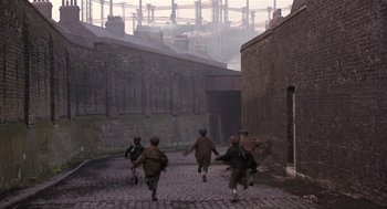 Movie still from “Chaplin” (1992), directed by Richard Attenborough – A group of people walking down a brick road; Extreme Wide shot, High angle