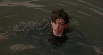 Movie still from “Chaplin” (1992), directed by Richard Attenborough – A man in a suit and glasses swimming in a body of water; Close Up shot, High angle