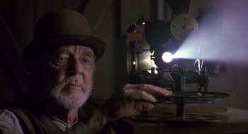 Movie still from “Chaplin” (1992), directed by Richard Attenborough – An old man in a hat and a hat looking at a projector; Close Up shot, Low angle