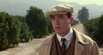 Movie still from “Chaplin” (1992), directed by Richard Attenborough – A man wearing a hat and a suit; Close Up shot, Over the shoulder angle