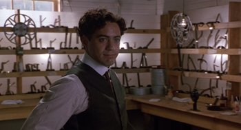Movie still from “Chaplin” (1992), directed by Richard Attenborough – A man standing in front of a room filled with tools; Medium shot, Low angle