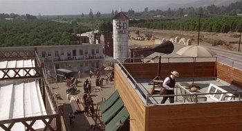 Movie still from “Chaplin” (1992), directed by Richard Attenborough – An aerial view of an old western town with people on the rooftops; Extreme Wide shot, High angle