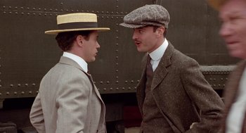 Movie still from “Chaplin” (1992), directed by Richard Attenborough – Two men in suits and hats talking to each other; Close Up shot, Over the shoulder angle
