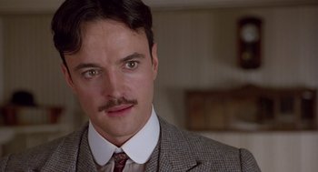 Movie still from “Chaplin” (1992), directed by Richard Attenborough – A person wearing a suit and tie; Close Up shot, Low angle