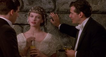 Movie still from “Chaplin” (1992), directed by Richard Attenborough – A man and a woman in formal wear holding drinks; Medium shot, Over the shoulder angle