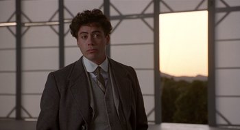 Movie still from “Chaplin” (1992), directed by Richard Attenborough – A man in a suit and tie standing in front of a window; Close Up shot, Low angle