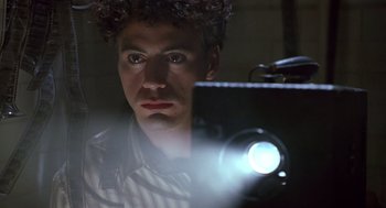 Movie still from “Chaplin” (1992), directed by Richard Attenborough – A man is looking into a mirror with a projector in front of him; Close Up shot, Low angle