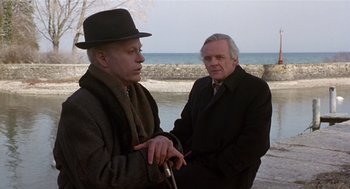 Movie still from “Chaplin” (1992), directed by Richard Attenborough – Two older men standing next to each other near a body of water; Medium shot, Over the shoulder angle