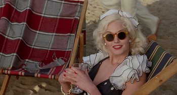 Movie still from “Chaplin” (1992), directed by Richard Attenborough – A woman sitting on a chair holding a drink; Medium shot, High angle