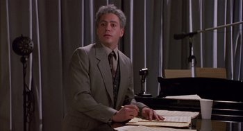 Movie still from “Chaplin” (1992), directed by Richard Attenborough – A man sitting at a table in front of a phone; Medium shot, High angle