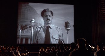 Movie still from “Chaplin” (1992), directed by Richard Attenborough – People watching a movie with a man in a uniform on the screen; Wide shot, Low angle