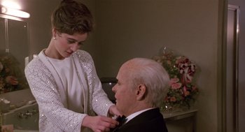 Movie still from “Chaplin” (1992), directed by Richard Attenborough – An older man and a young woman are fixing a tie; Medium shot, Over the shoulder angle