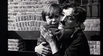 Movie still from “Chaplin” (1992), directed by Richard Attenborough – An old photo of a man holding a young boy; Close Up shot, Low angle