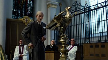 Movie still from “Chariots of Fire” (1981), directed by Hugh Hudson – A man standing next to an eagle statue in a church; Medium shot, Low angle