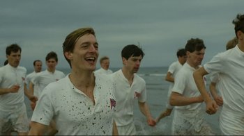 Movie still from “Chariots of Fire” (1981), directed by Hugh Hudson – A group of young men standing on top of a sandy beach; Medium shot, Low angle