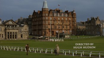 Movie still from “Chariots of Fire” (1981), directed by Hugh Hudson – Two men are standing in front of a large building; Extreme Wide shot, High angle