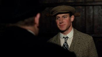 Movie still from “Chariots of Fire” (1981), directed by Hugh Hudson – A man wearing a hat and a tie; Close Up shot, Over the shoulder angle
