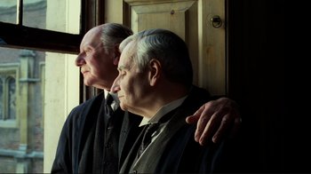Movie still from “Chariots of Fire” (1981), directed by Hugh Hudson – Two older men standing next to each other near a window; Medium shot, Low angle