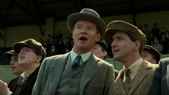 Movie still from “Chariots of Fire” (1981), directed by Hugh Hudson – A man in a suit and a hat standing next to another man in a suit and a hat; Close Up shot, Low angle