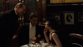 Movie still from “Chariots of Fire” (1981), directed by Hugh Hudson – A group of people sitting at a table with drinks; Medium shot, Over the shoulder angle