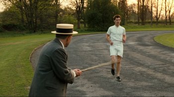 Movie still from “Chariots of Fire” (1981), directed by Hugh Hudson – A man holding a baseball bat while another man runs by; Medium shot, Over the shoulder angle