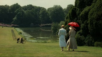 Movie still from “Chariots of Fire” (1981), directed by Hugh Hudson – Two women are standing in the grass with an umbrella; Extreme Wide shot, Over the shoulder angle